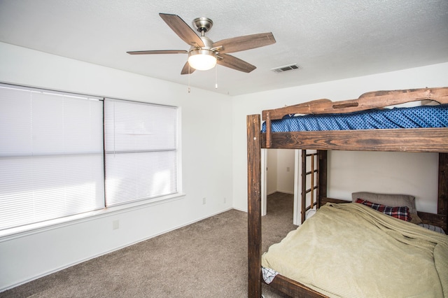 unfurnished bedroom with carpet flooring, visible vents, a textured ceiling, and ceiling fan