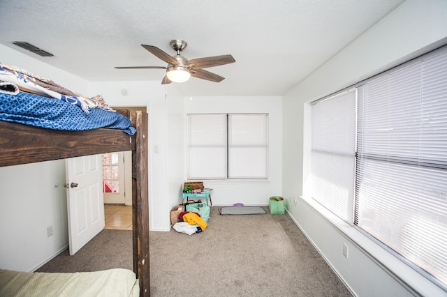 unfurnished bedroom featuring a textured ceiling, ceiling fan, carpet, and visible vents