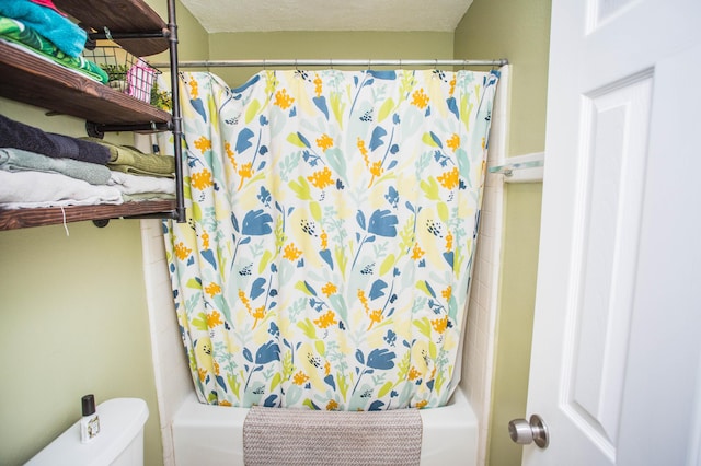 bathroom featuring shower / bath combination with curtain, a textured ceiling, and toilet