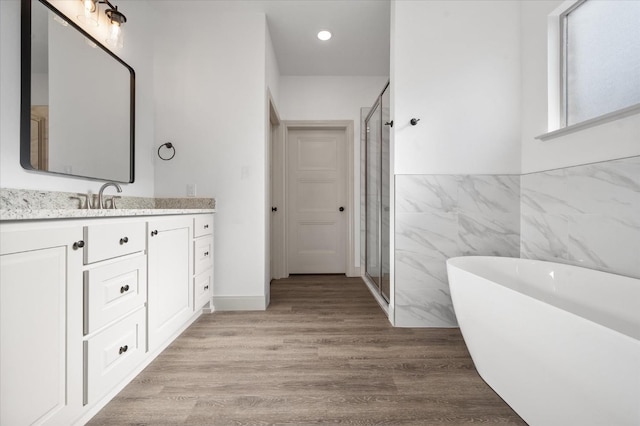 bathroom featuring hardwood / wood-style flooring, vanity, independent shower and bath, and tile walls