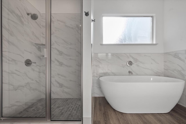 bathroom with tile walls, hardwood / wood-style floors, and independent shower and bath