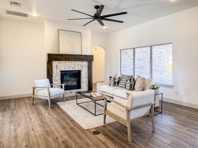 living room featuring a stone fireplace, hardwood / wood-style floors, and ceiling fan