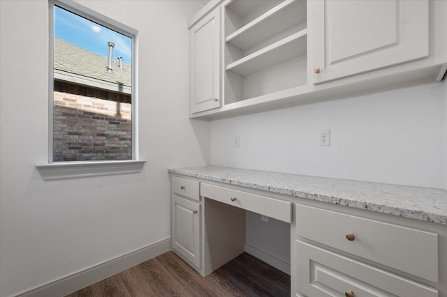 unfurnished office with dark hardwood / wood-style flooring and built in desk