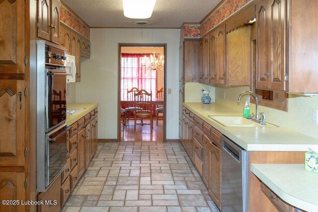 303 Comanche Trl, Tulia, TX 79088 - kitchen featuring stainless steel dishwasher, light countertops, a textured ceiling, and brown cabinetry