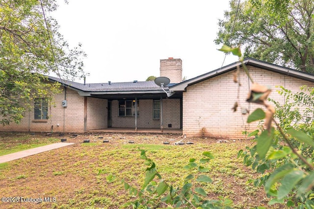 303 Comanche Trl, Tulia, TX 79088 - back of house with a chimney, brick siding, and a patio