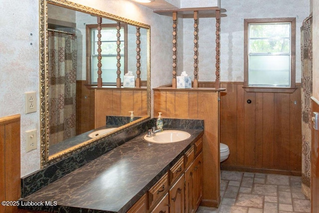 303 Comanche Trl, Tulia, TX 79088 - full bathroom featuring a wainscoted wall, vanity, wood walls, a shower, and brick patterned flooring