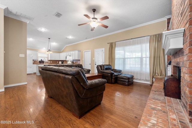 1507 Nottingham Ave, Wolfforth, TX 79382 - living room with ornamental molding, wood finished floors, a ceiling fan, a brick fireplace, and baseboards