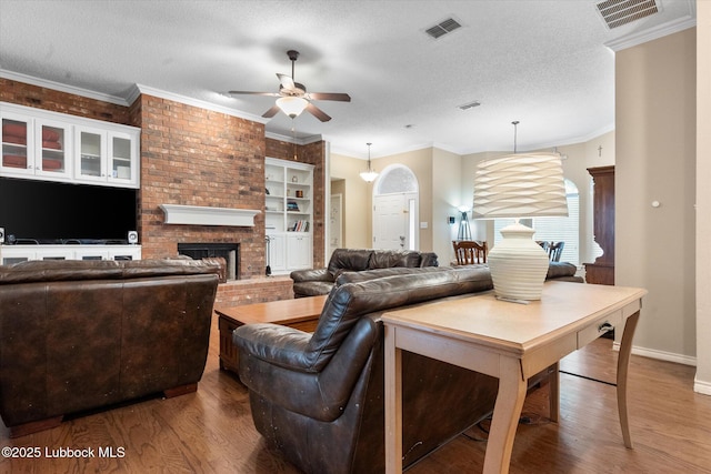 1507 Nottingham Ave, Wolfforth, TX 79382 - living room featuring wood finished floors, a ceiling fan, a fireplace, baseboards, and a textured ceiling