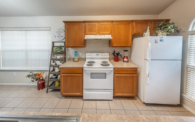 kitchen featuring light tile patterned floors, light countertops, brown cabinetry, white appliances, and under cabinet range hood