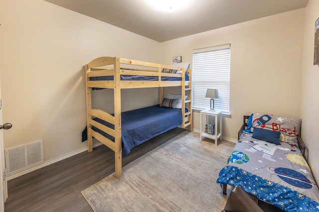 bedroom with wood finished floors, visible vents, and baseboards