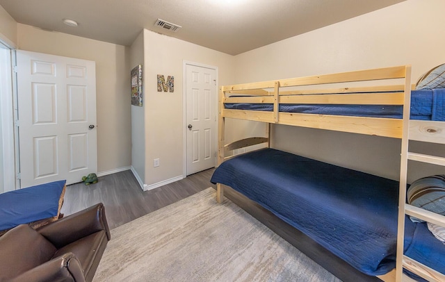 bedroom featuring wood finished floors, visible vents, and baseboards