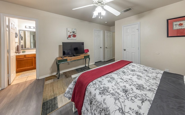 bedroom featuring baseboards, visible vents, a ceiling fan, wood finished floors, and ensuite bathroom