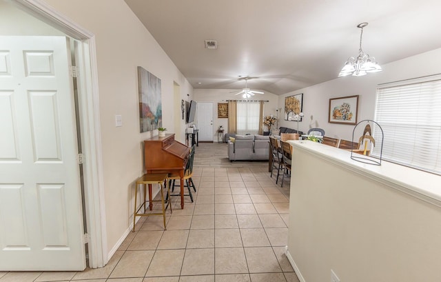 kitchen with ceiling fan with notable chandelier, a glass covered fireplace, a healthy amount of sunlight, and light tile patterned floors