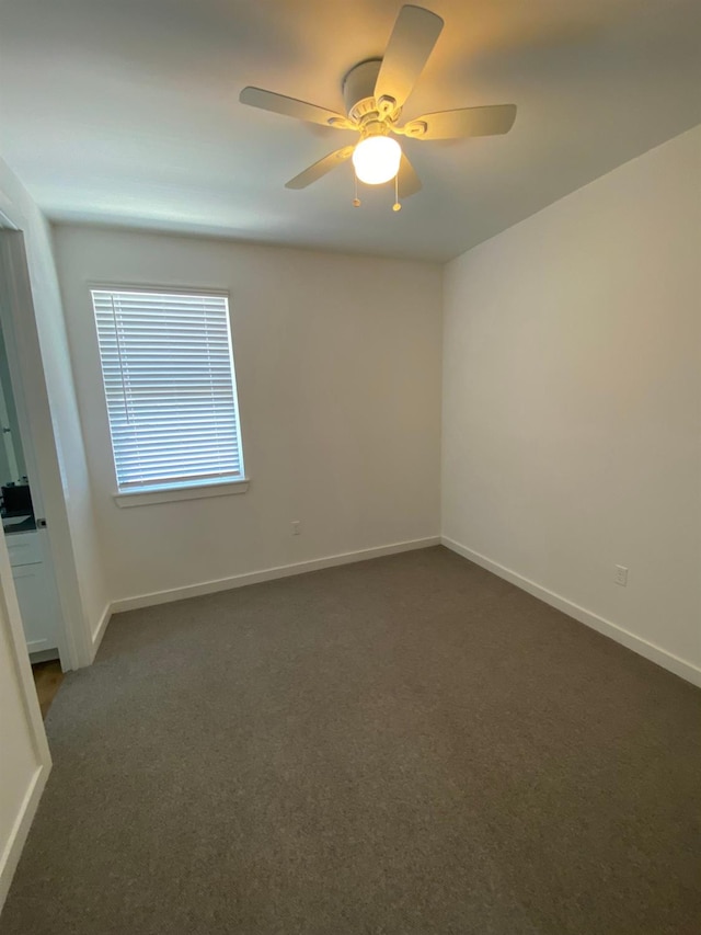 unfurnished room with ceiling fan and dark carpet