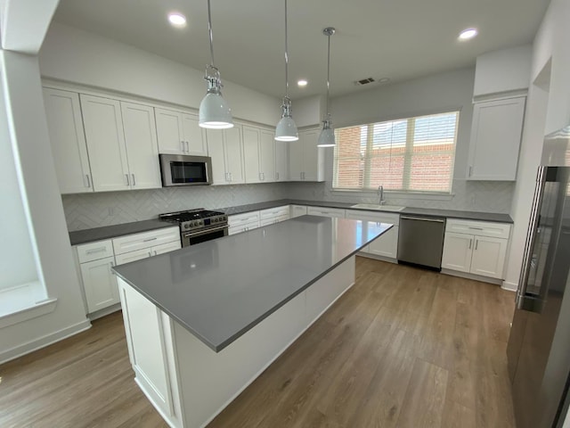 kitchen with stainless steel appliances, sink, a kitchen island, and white cabinets