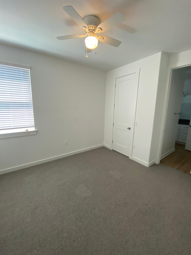 unfurnished bedroom featuring dark carpet and ceiling fan