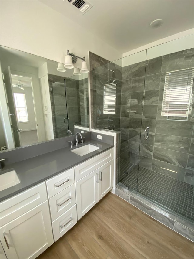 bathroom featuring hardwood / wood-style flooring, vanity, and a shower with shower door