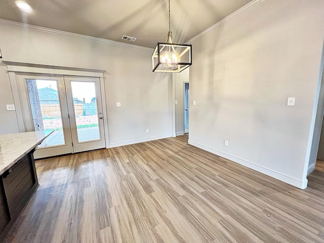 unfurnished dining area with french doors, ornamental molding, a chandelier, and light wood-type flooring