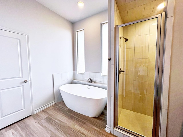 bathroom with wood-type flooring and shower with separate bathtub