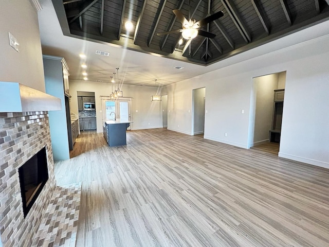 unfurnished living room with light hardwood / wood-style flooring, ceiling fan, a fireplace, wooden ceiling, and beamed ceiling