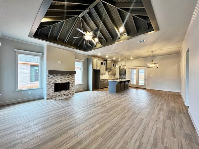 unfurnished living room with ceiling fan, a brick fireplace, a healthy amount of sunlight, and light hardwood / wood-style floors