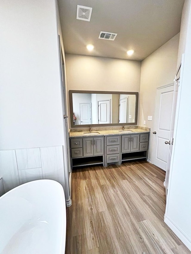 bathroom with vanity, wood-type flooring, and a bath