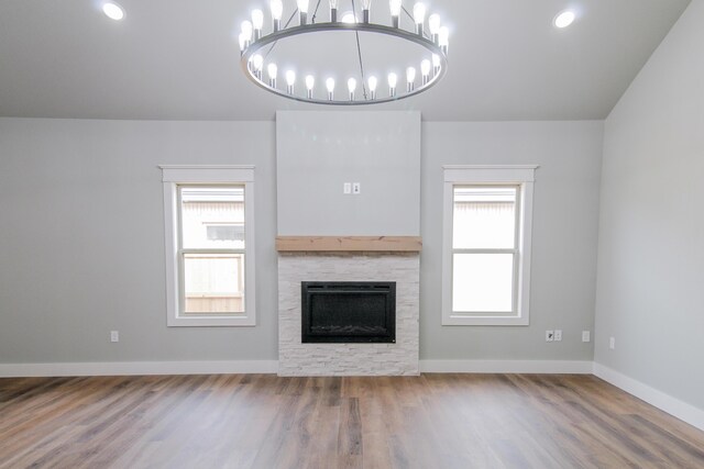 unfurnished living room with wood finished floors, baseboards, an inviting chandelier, recessed lighting, and a fireplace