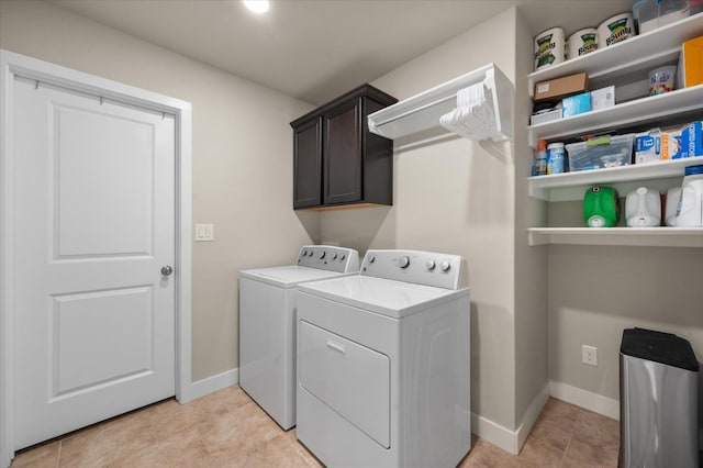 clothes washing area featuring cabinets, washing machine and clothes dryer, and light tile patterned flooring