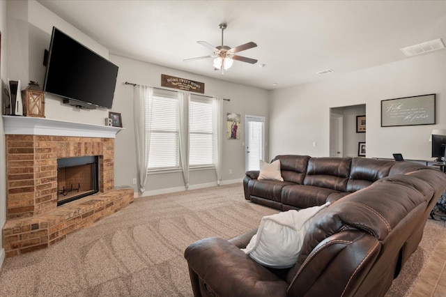 carpeted living room featuring a fireplace and ceiling fan