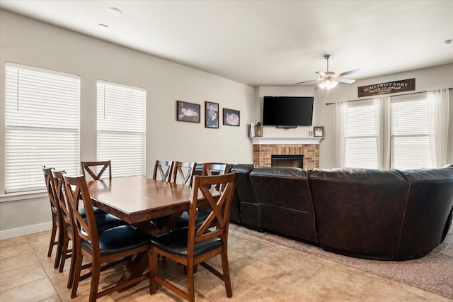 dining space featuring ceiling fan, light tile patterned floors, and a fireplace