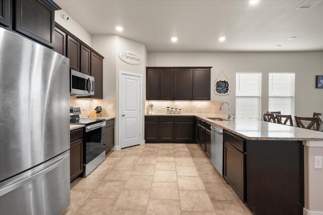 kitchen with dark brown cabinetry, stainless steel appliances, sink, and decorative backsplash