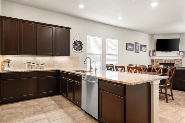 kitchen featuring a breakfast bar, dishwasher, sink, backsplash, and kitchen peninsula