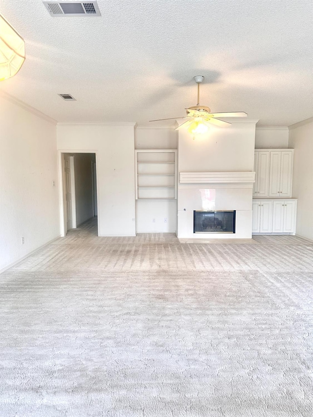 unfurnished living room with ornamental molding, light colored carpet, a textured ceiling, and ceiling fan