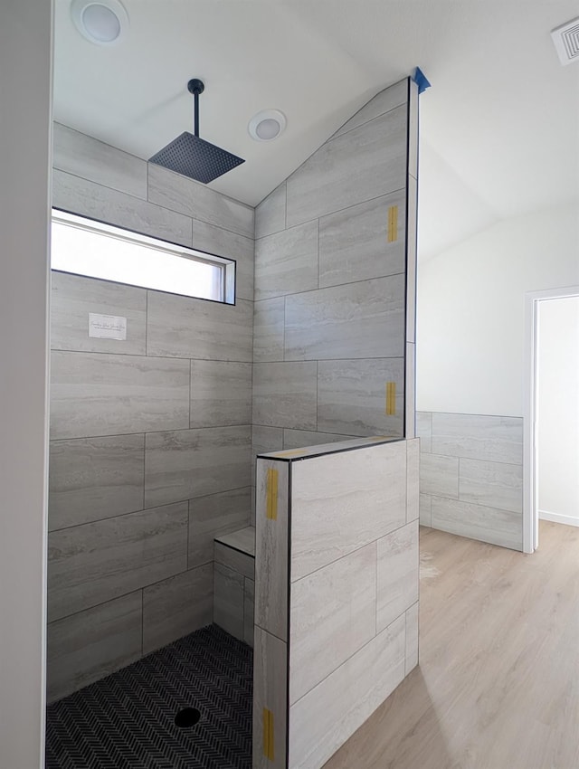 bathroom with vaulted ceiling, wood-type flooring, and tiled shower