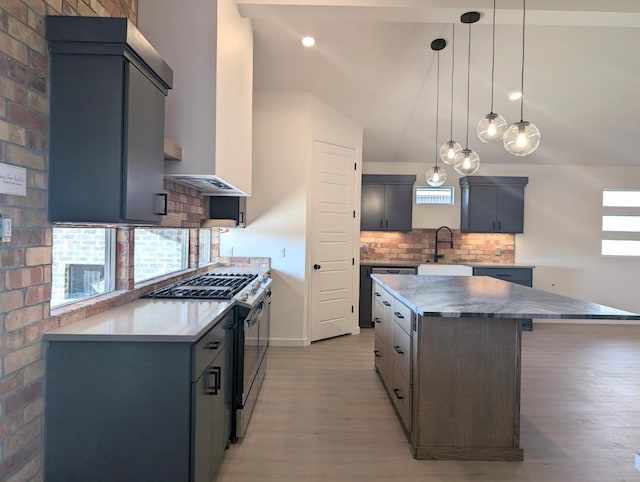 kitchen featuring a kitchen island, pendant lighting, tasteful backsplash, sink, and stainless steel range with gas stovetop