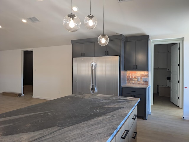 kitchen featuring hanging light fixtures, high end fridge, backsplash, and light hardwood / wood-style flooring