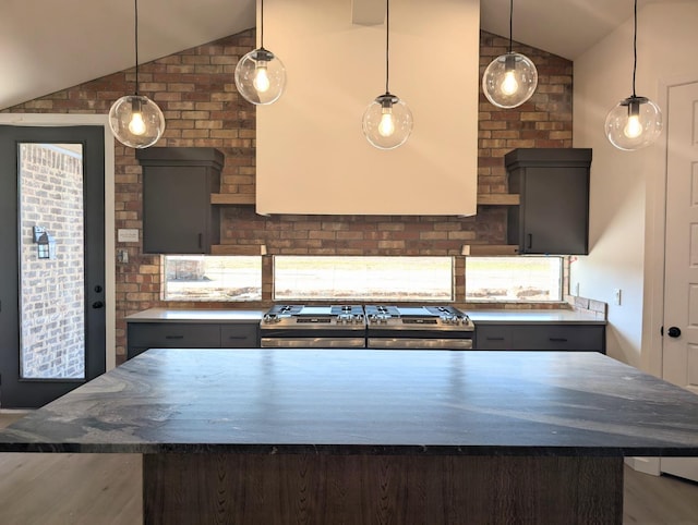 kitchen featuring vaulted ceiling, a kitchen island, pendant lighting, and stainless steel range oven