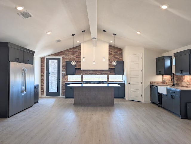 kitchen with sink, hanging light fixtures, a kitchen island, a wealth of natural light, and stainless steel appliances