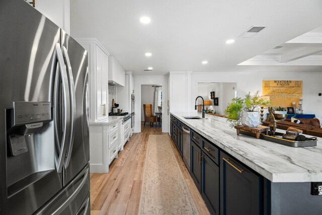 kitchen featuring white cabinetry, stainless steel refrigerator with ice dispenser, sink, and light wood-type flooring