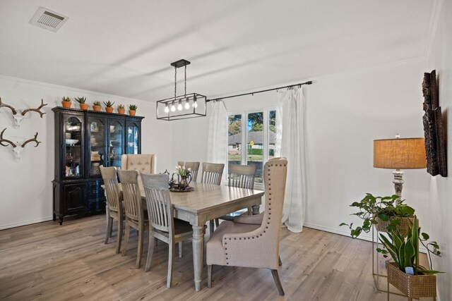 dining space featuring ornamental molding and light hardwood / wood-style flooring