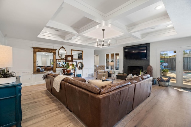 living room featuring coffered ceiling, a brick fireplace, beam ceiling, and light hardwood / wood-style floors