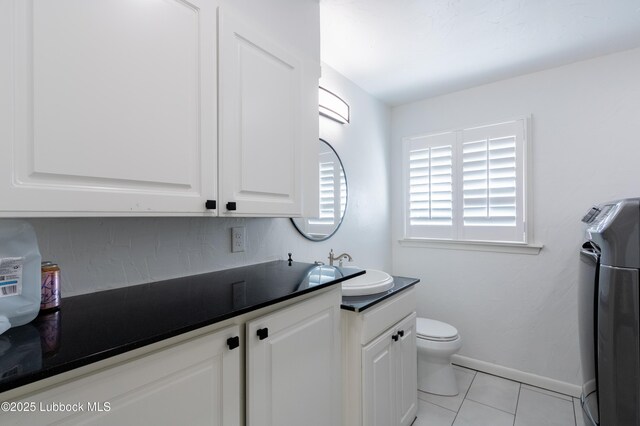 3014 25th St, Lubbock, TX 79410 - bathroom with vanity, toilet, tile patterned floors, baseboards, and washer / dryer