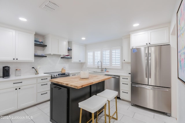 3014 25th St, Lubbock, TX 79410 - kitchen featuring appliances with stainless steel finishes, open shelves, wooden counters, a sink, and light tile patterned floors