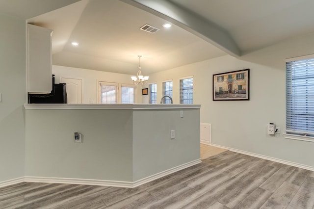 interior space featuring white cabinetry, an inviting chandelier, decorative light fixtures, light wood-type flooring, and black refrigerator