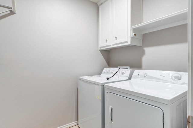 clothes washing area with cabinets and washing machine and clothes dryer