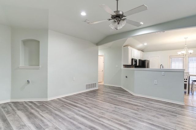 unfurnished living room with lofted ceiling, sink, ceiling fan with notable chandelier, and light hardwood / wood-style flooring