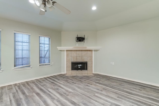 unfurnished living room with ceiling fan, a fireplace, and light hardwood / wood-style flooring