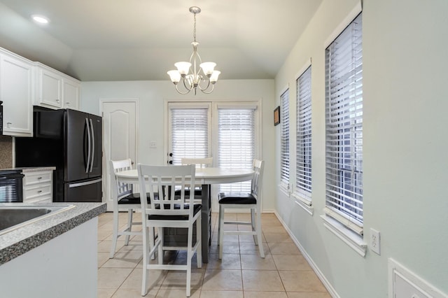 tiled dining space with vaulted ceiling and a chandelier