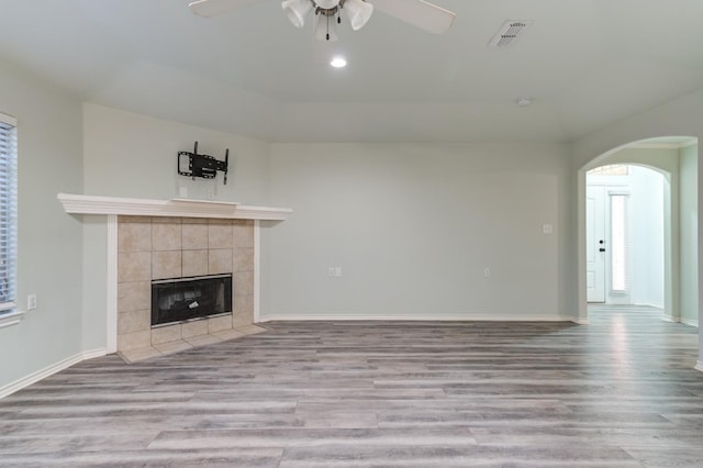 unfurnished living room with ceiling fan, a fireplace, and light hardwood / wood-style floors