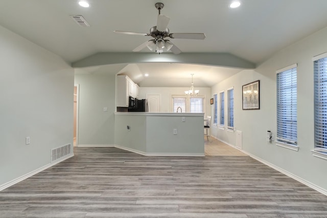 unfurnished living room with vaulted ceiling, ceiling fan with notable chandelier, and light hardwood / wood-style flooring